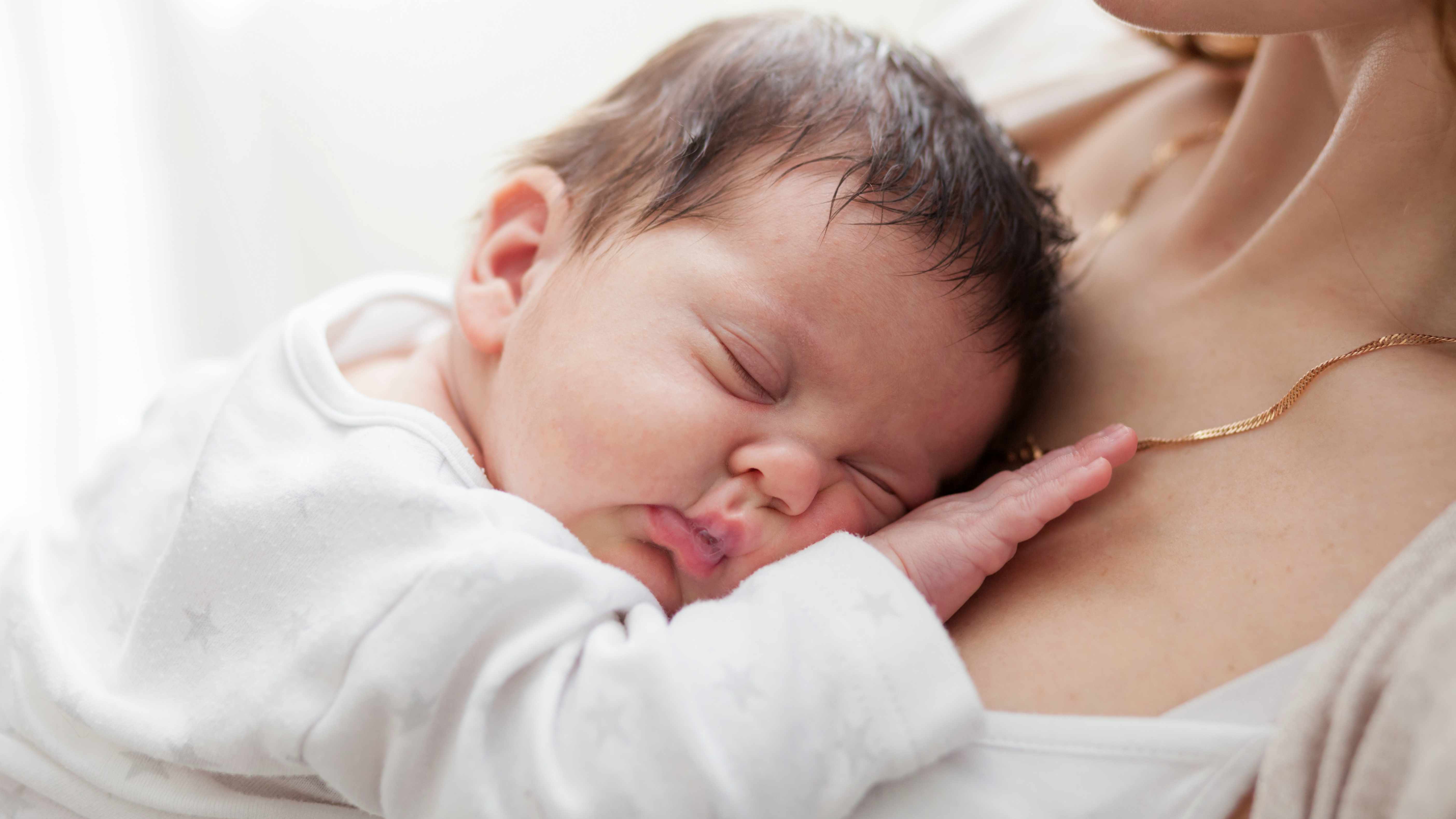 infant sleeping on mother's chest