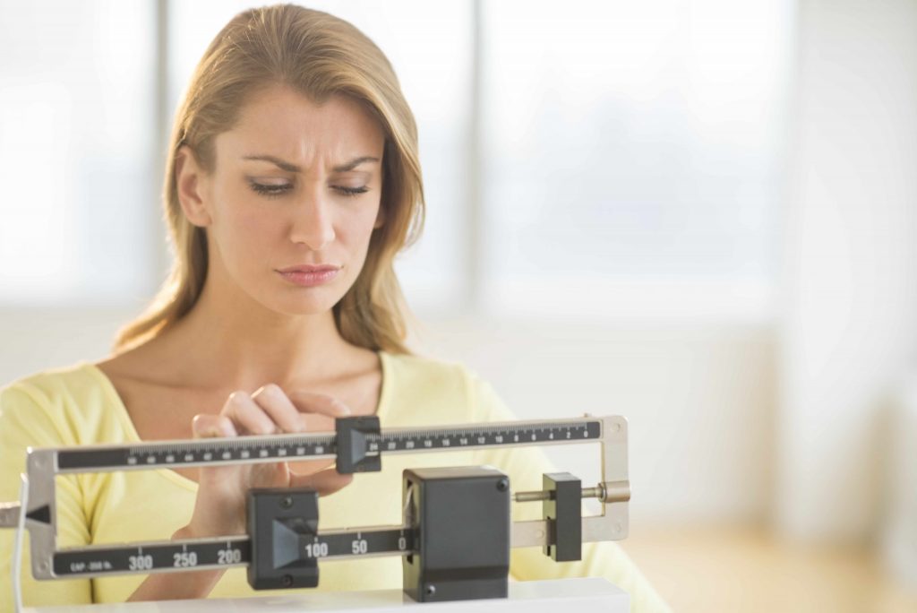 a woman on a weight scale looking disappointed