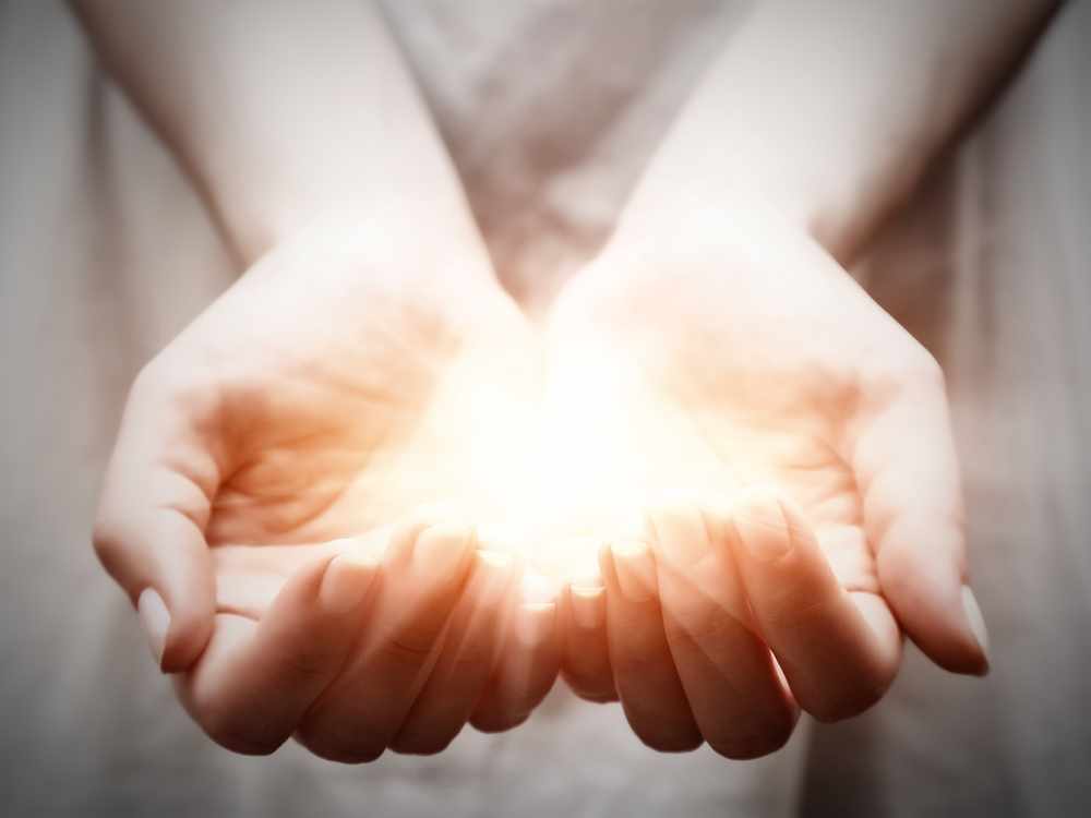 a woman holding a bright shining light in the palm of her hands