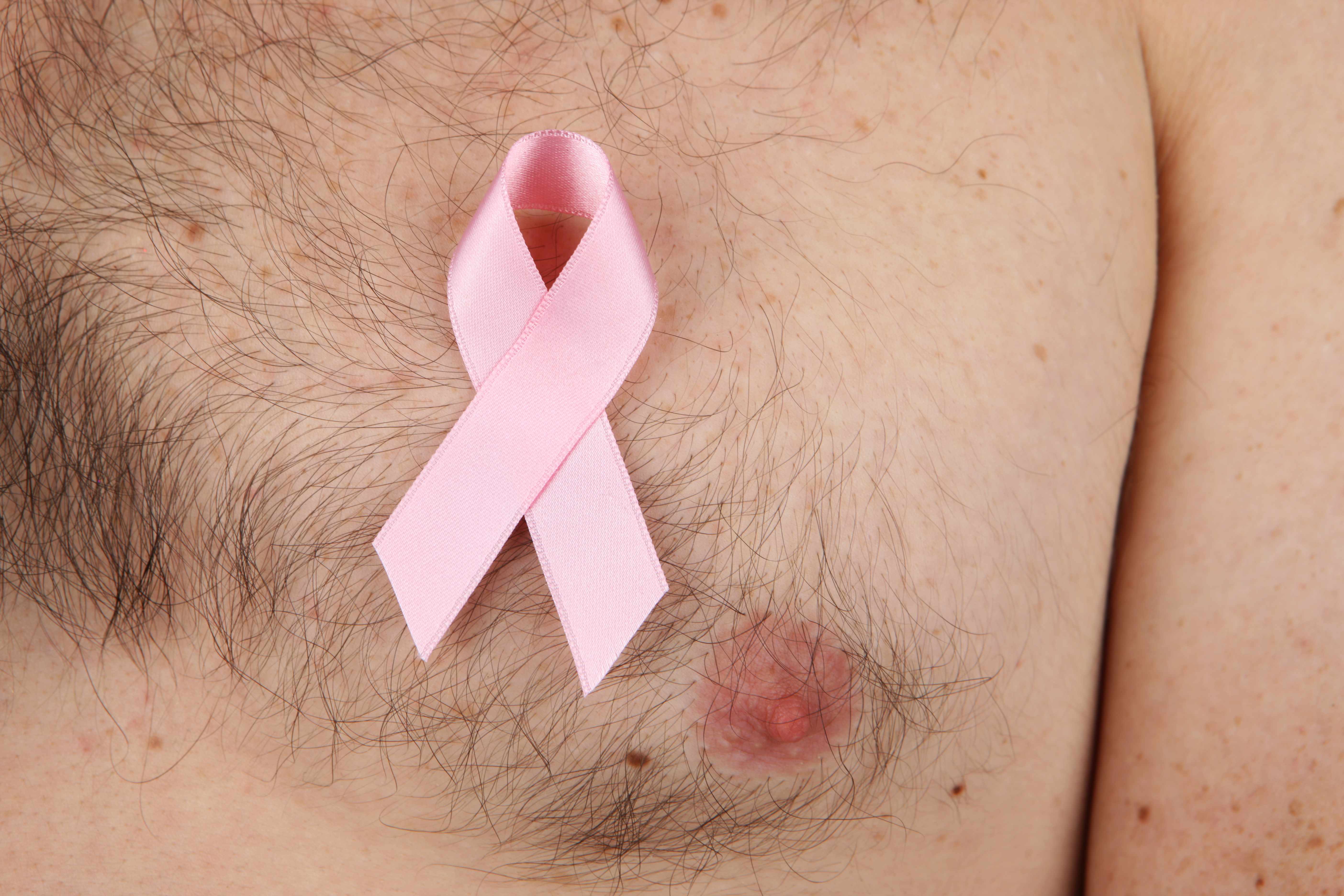a caucasian man's chest with a pink breast cancer ribbon
