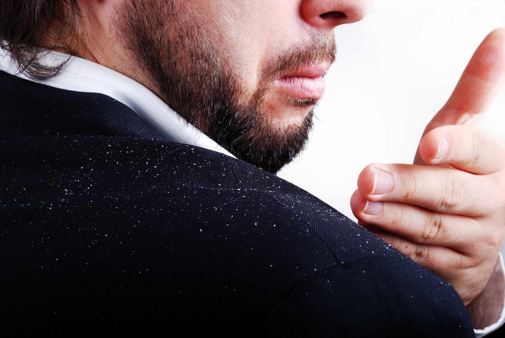 a businessman brushing flakes of dandruff off his jacket