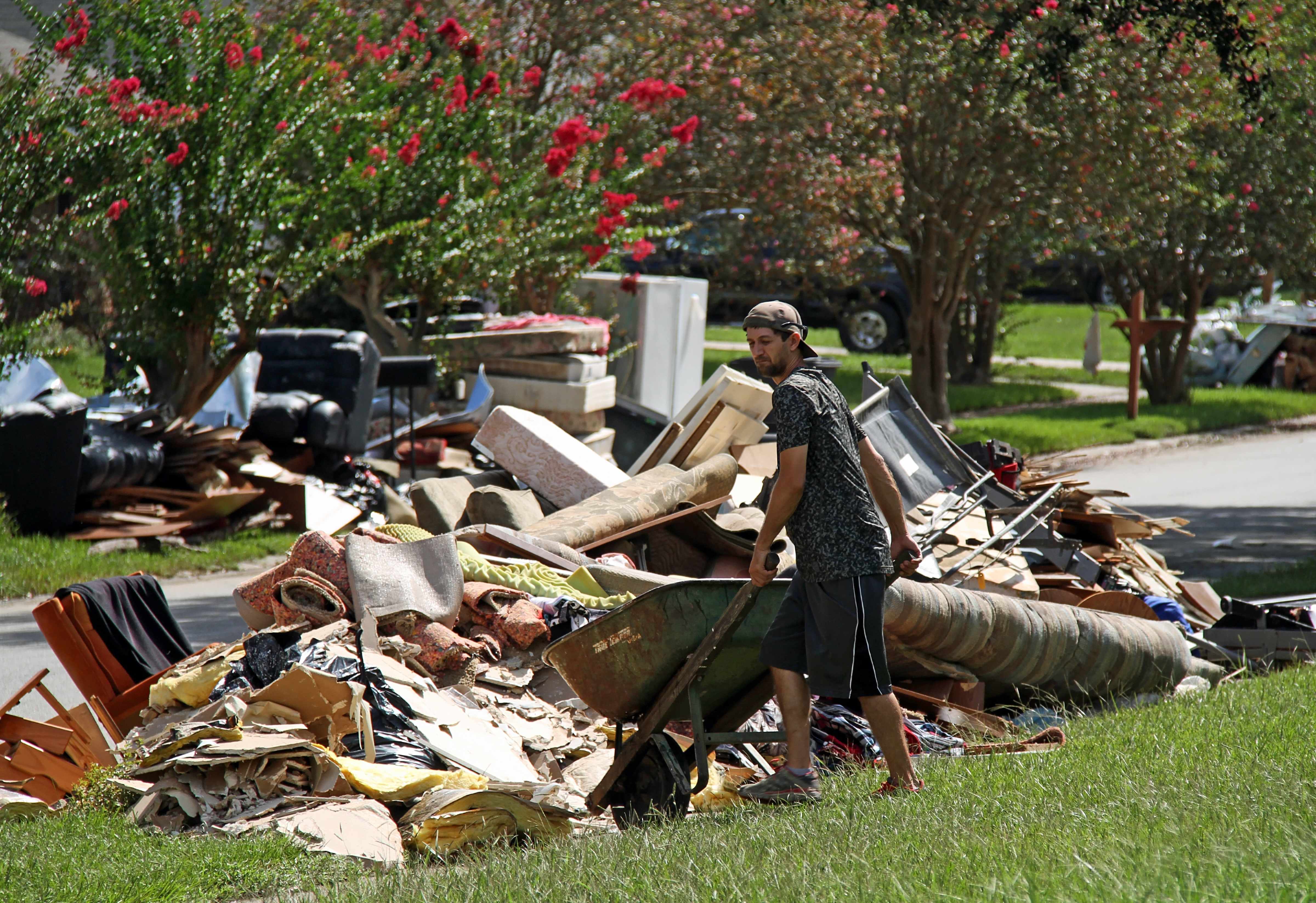 a man cleaning up storm debris with wheelbarrow