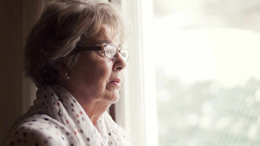 a profile close-up of a serious-looking older woman looking out a window