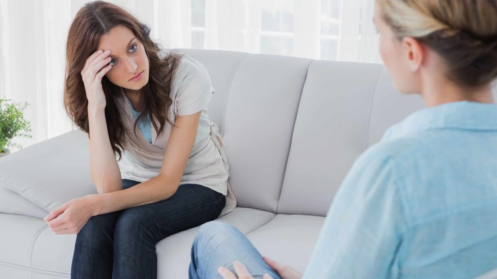 Una mujer joven conversa seriamente con una consejera