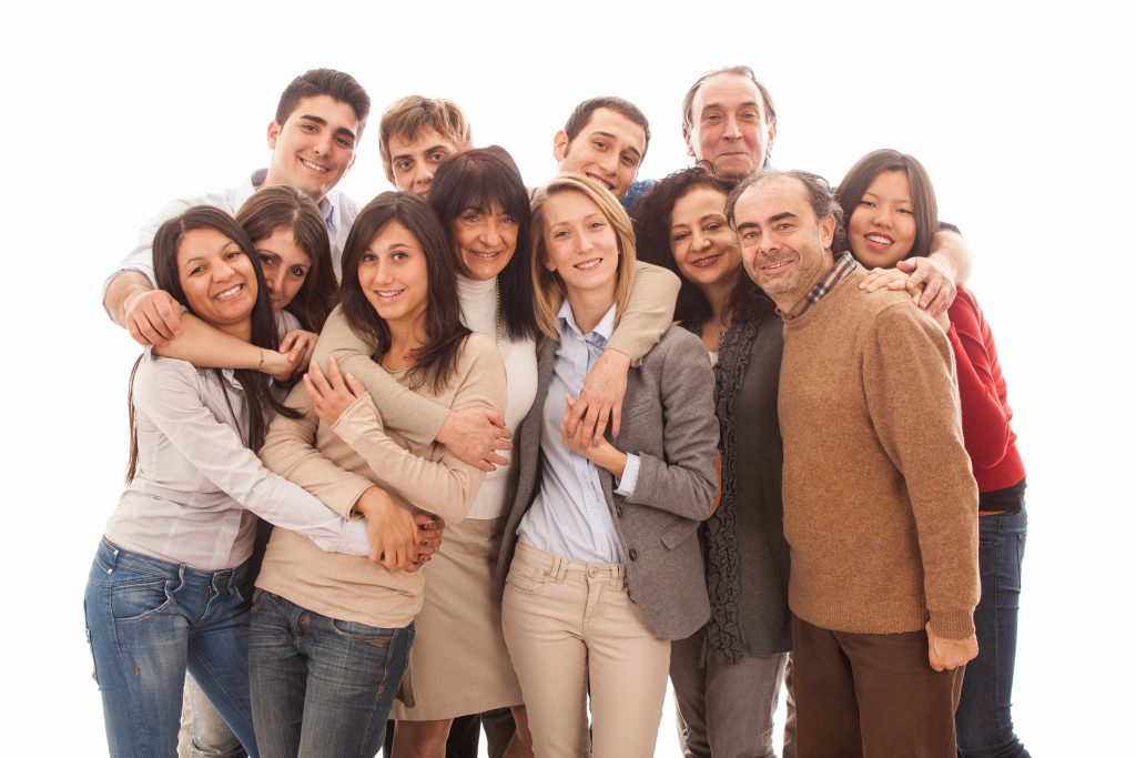 a multigenerational, multi-ethnic group of people standing together, smiling and hugging