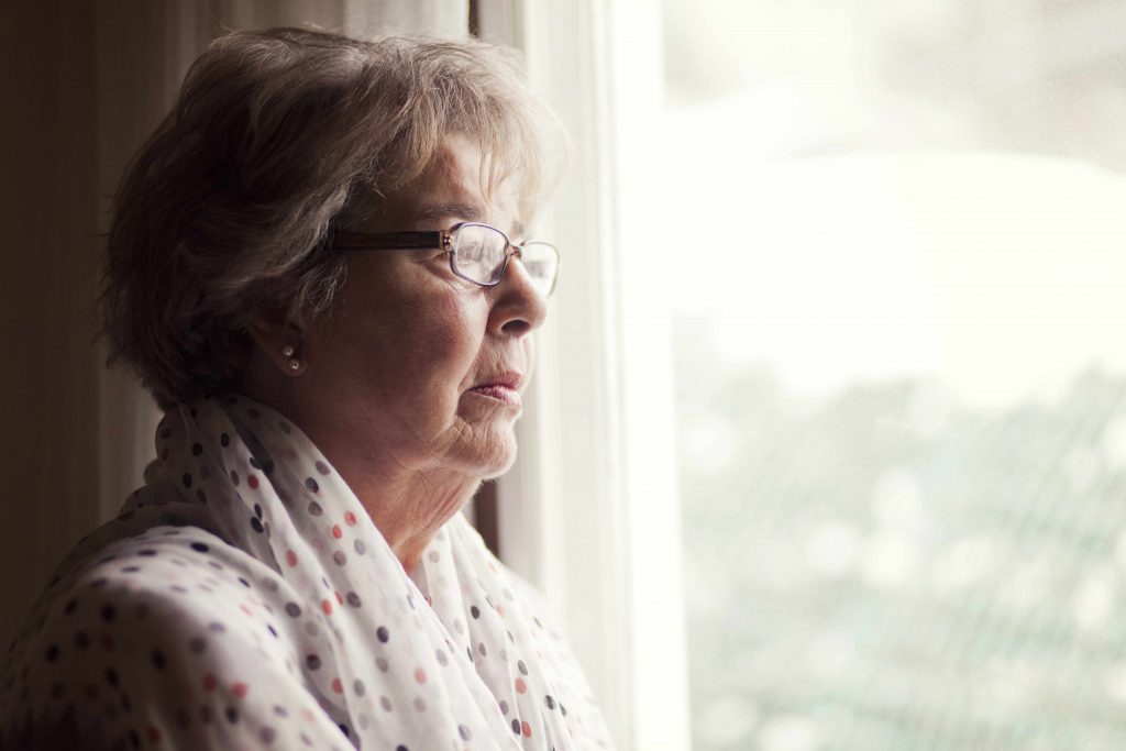 a profile close-up of a serious-looking older woman looking out a window
