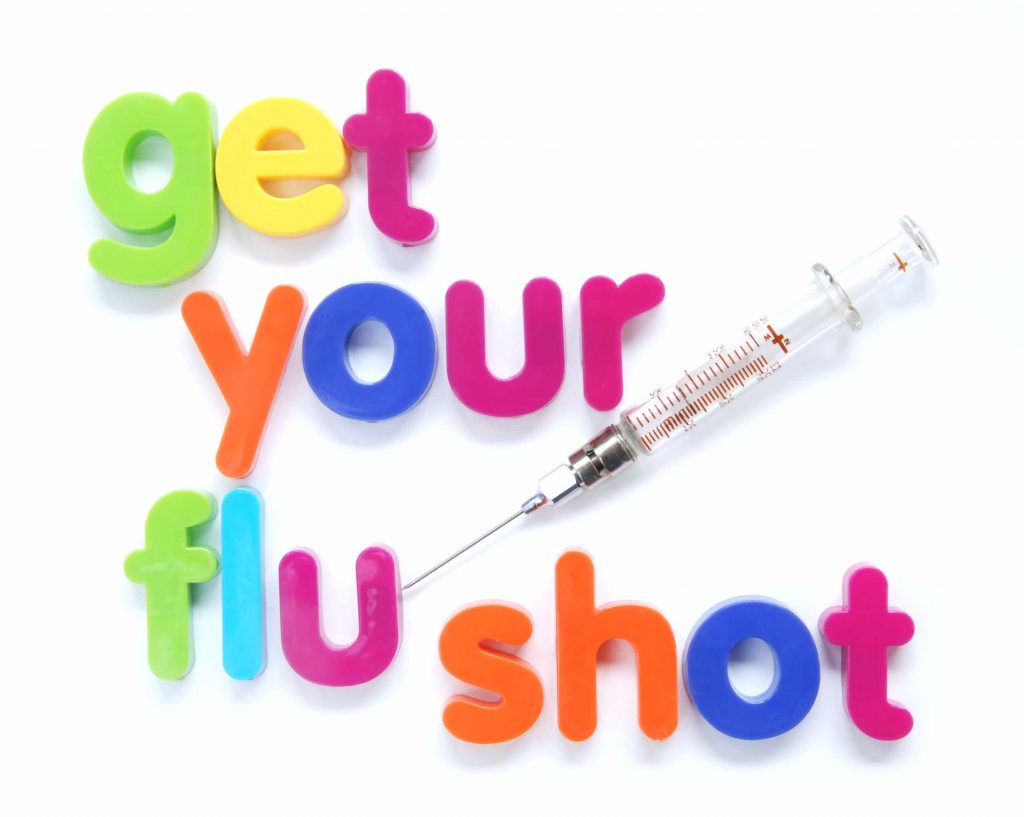 a syringe and child's magnet letters spelling out 'get your flu shot'