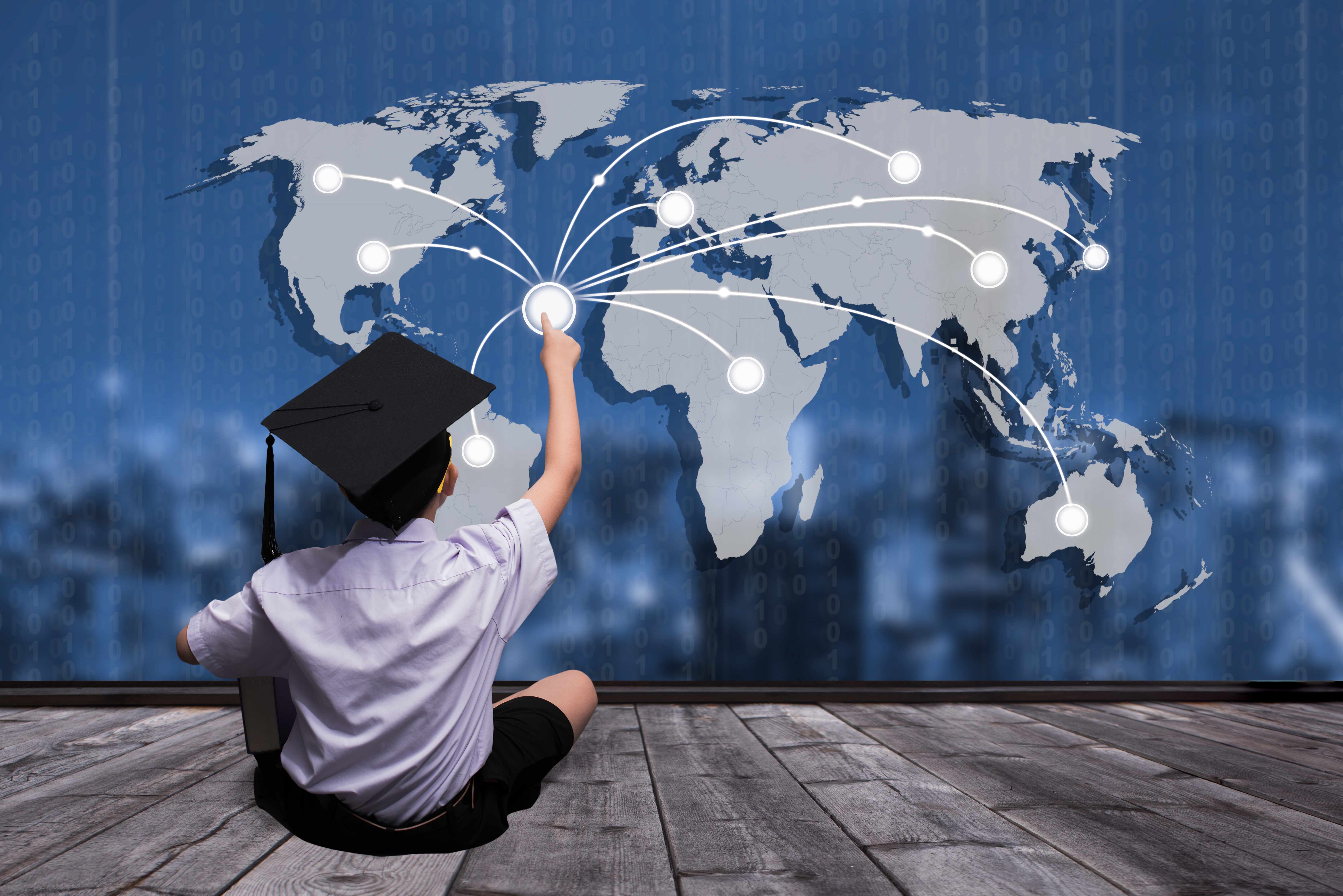a young boy with a graduation cap sitting in front of a global map