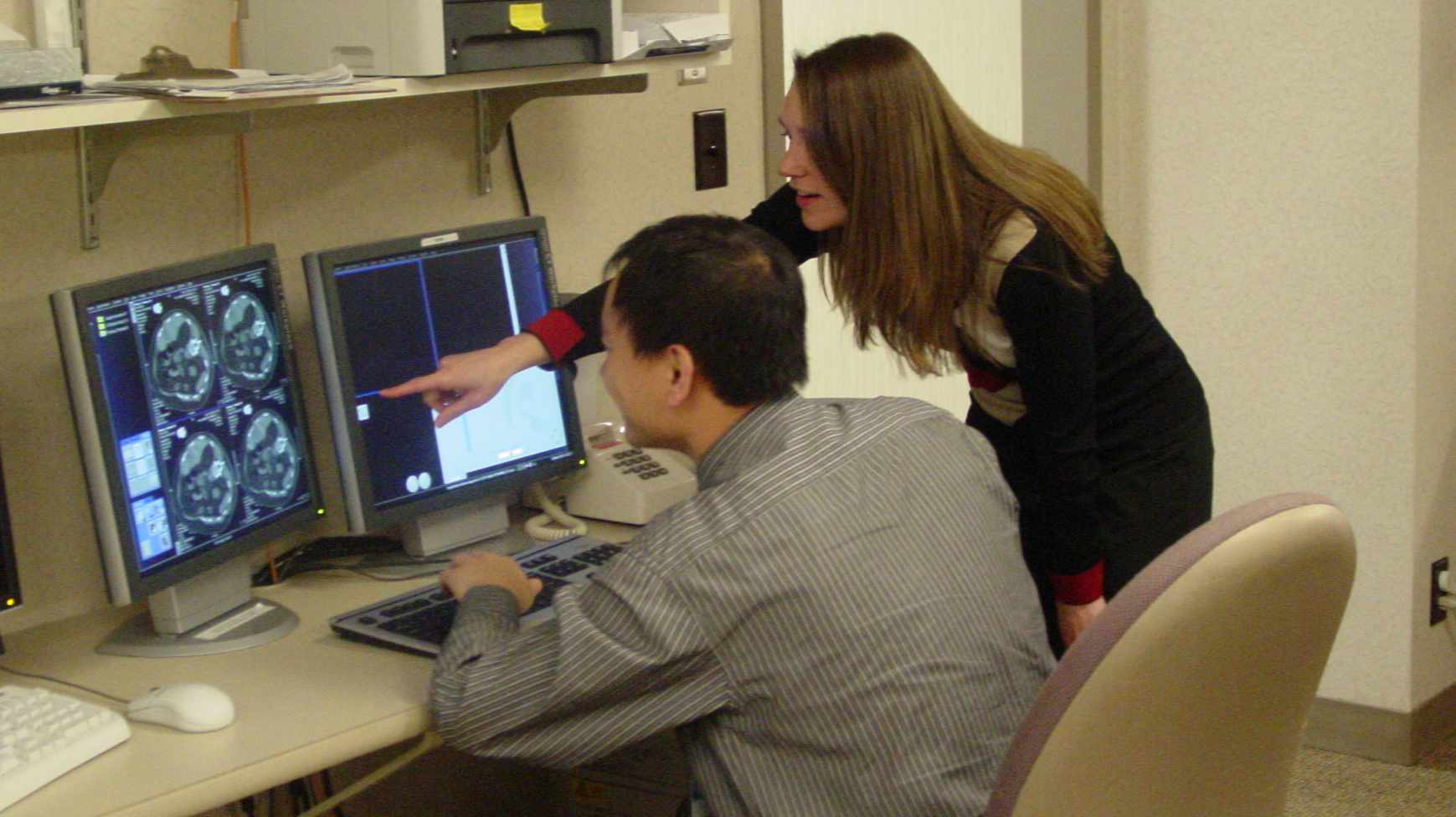 Two researchers looking at CT scan on computer