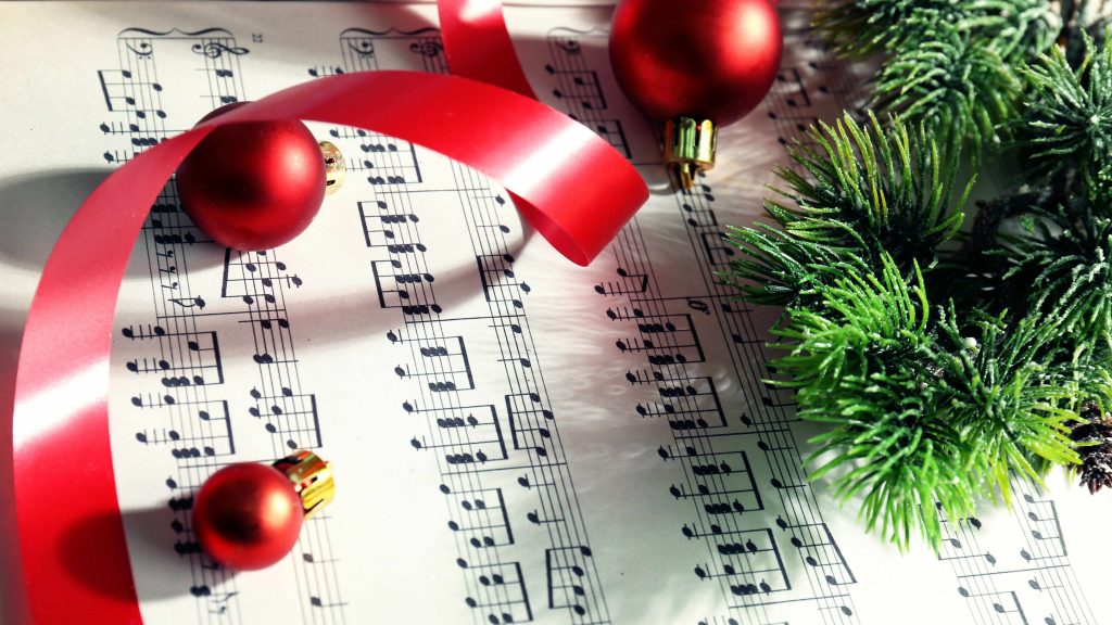 sheet music with holiday ornaments, ribbons and evergreen branches