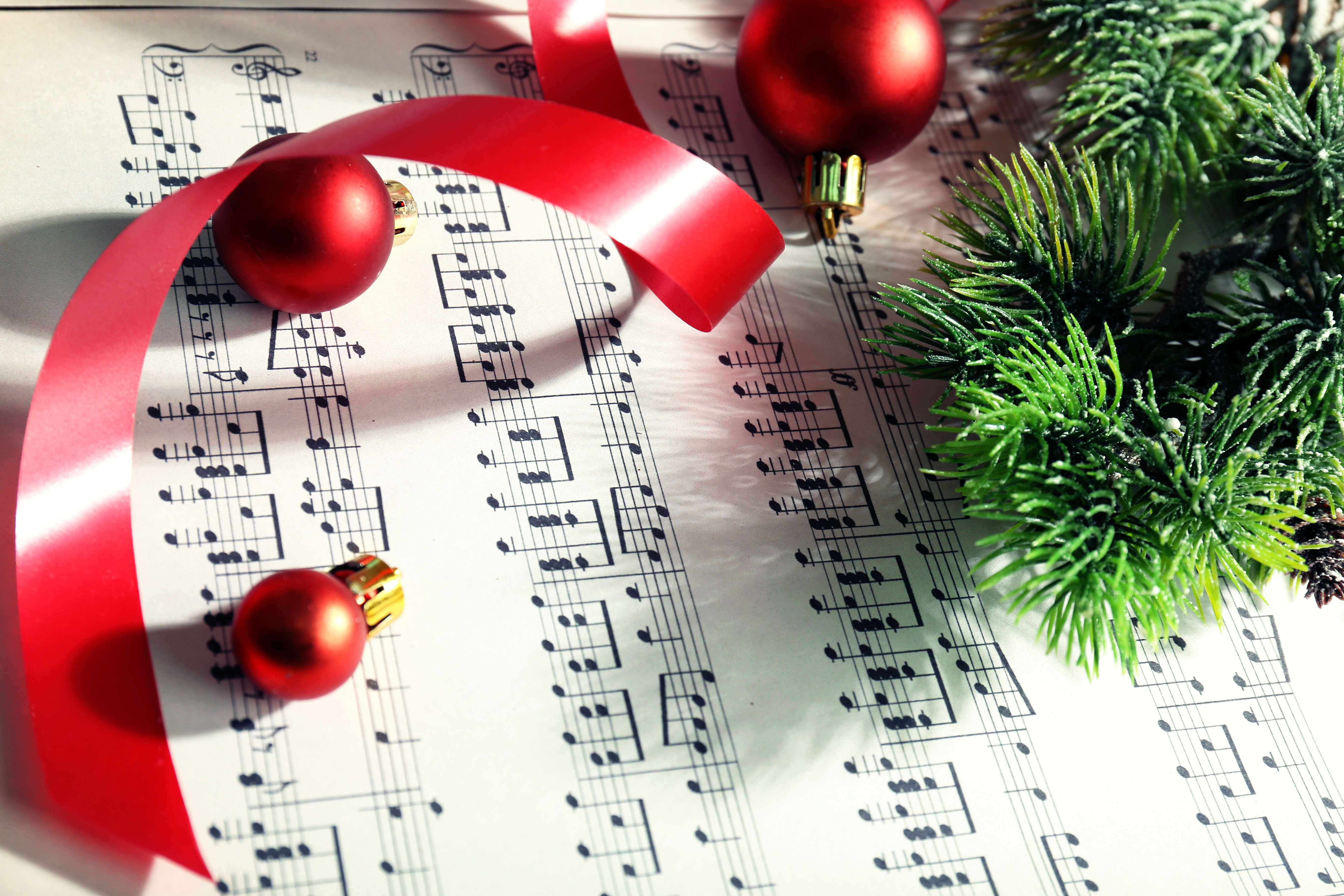 sheet music with holiday ornaments, ribbons and evergreen branches