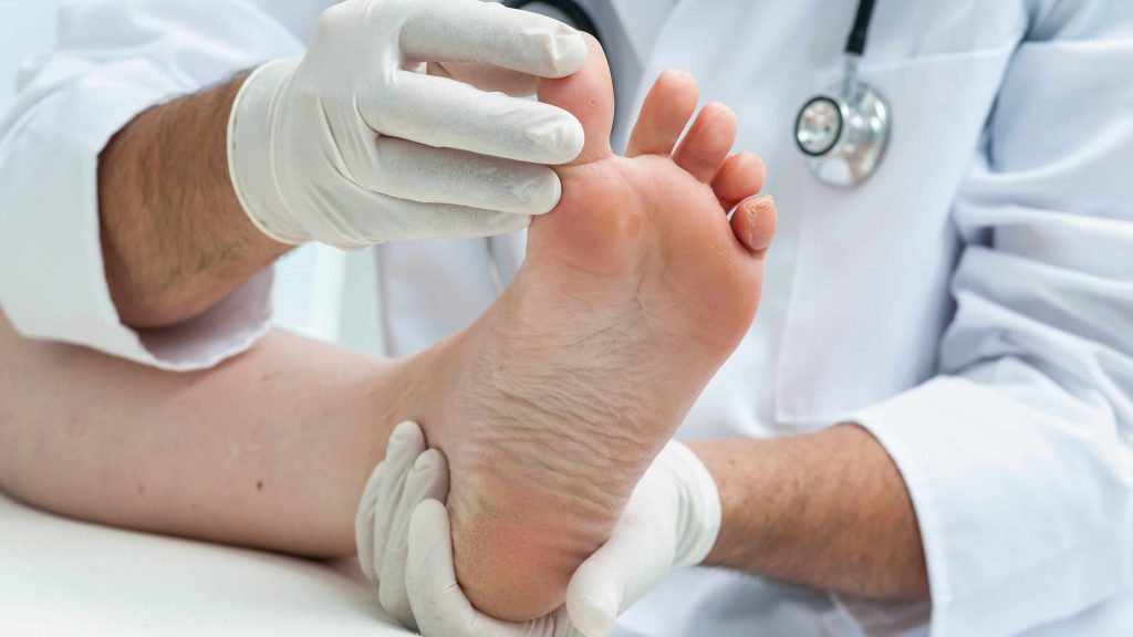 a medical person examining a person's foot for infection or athlete's foot