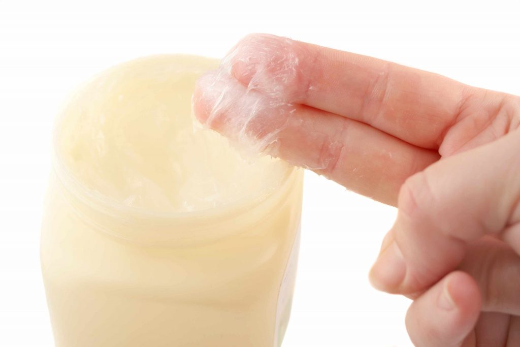Fingers dipped into a jar of vaseline petroleum jelly.