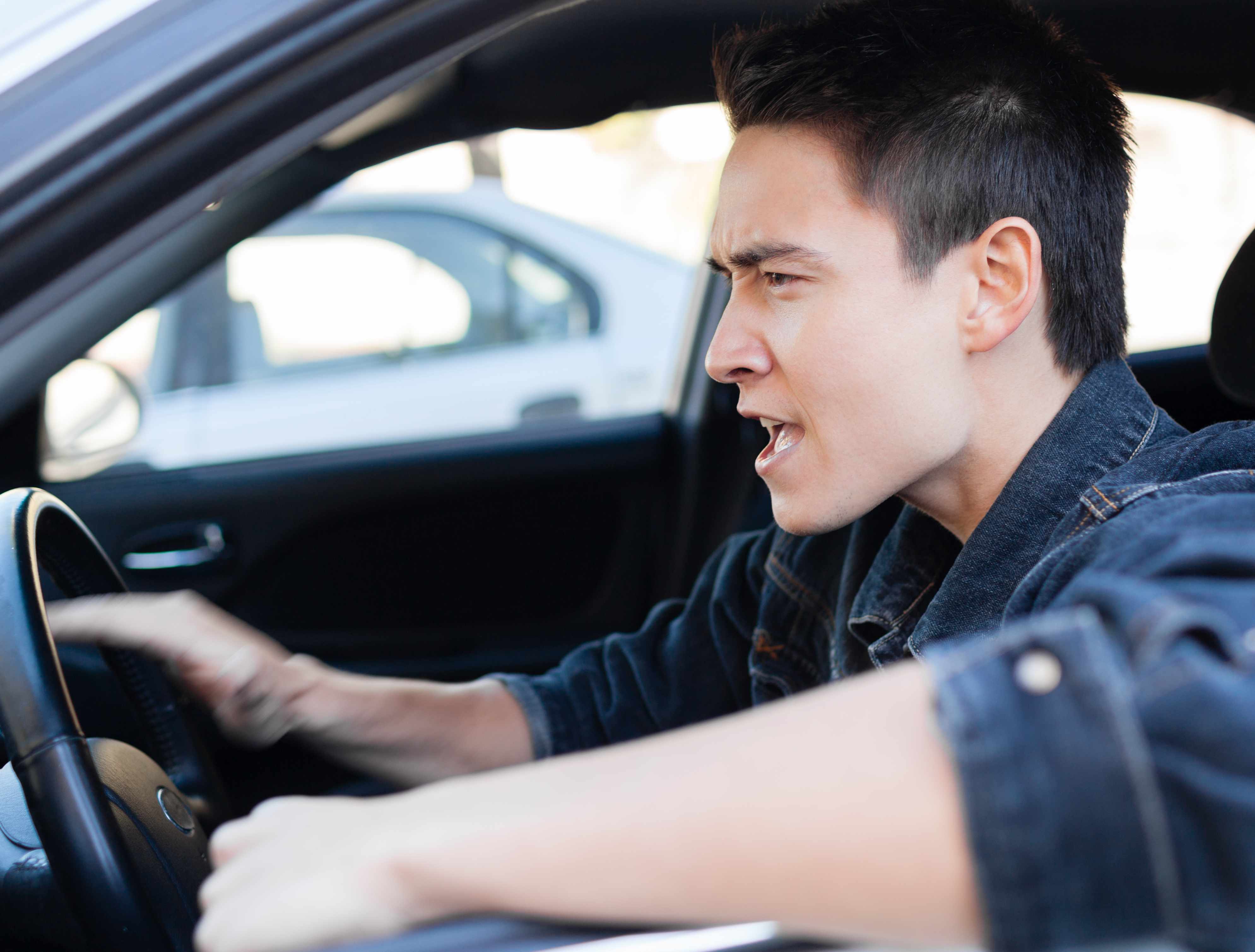 a young man driving angry behind the wheel, road rage