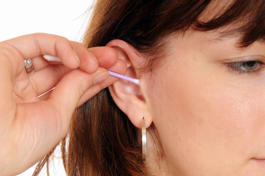 Una mujer joven intent limpiarse los oídos con un hisopo