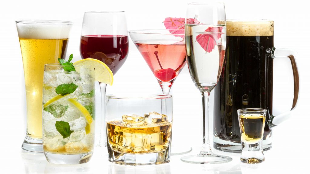 different kinds of alcoholic drinks in various glasses with a white background
