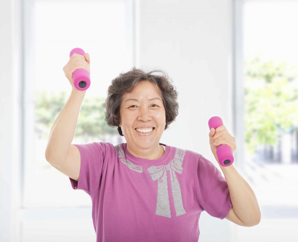 a smiling older woman, working out with hand weights