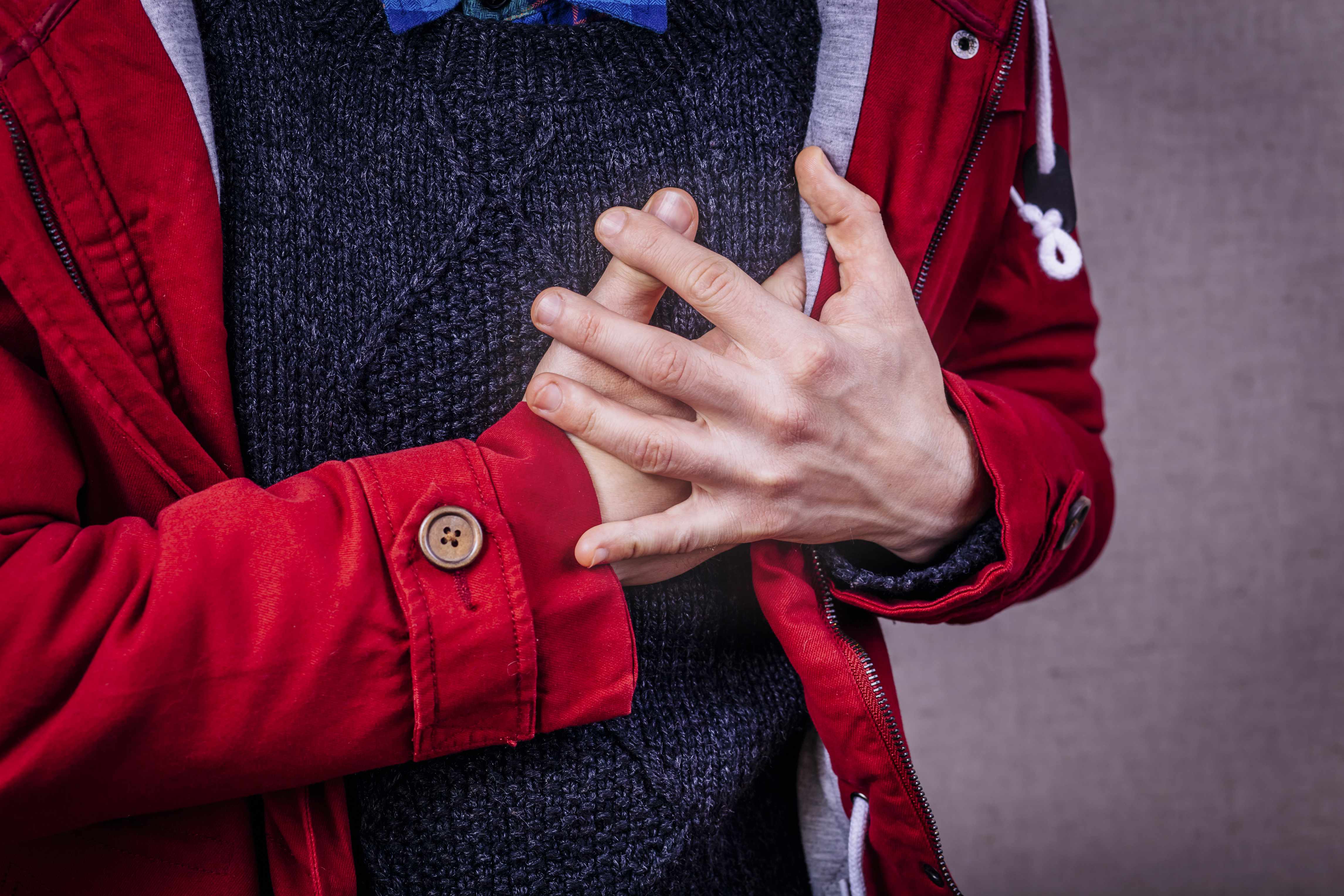 a person in a red coat holding chest with pain, perhaps a heart attack