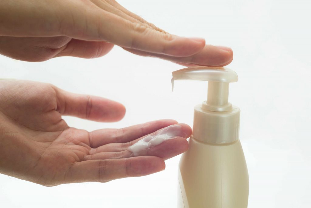 a close-up of two hands pumping lotion from a bottle