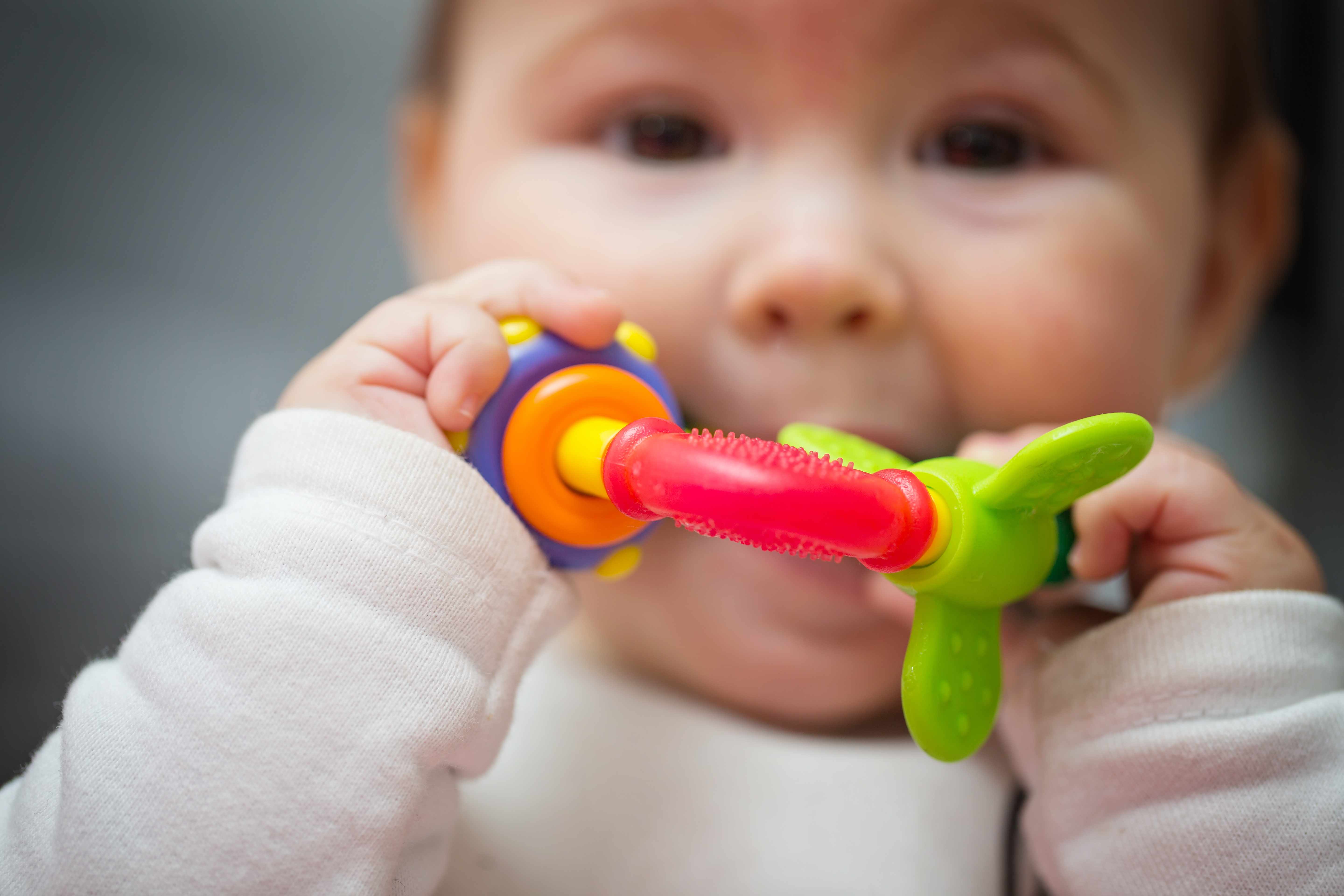 a baby chewing on a colorful teething ring