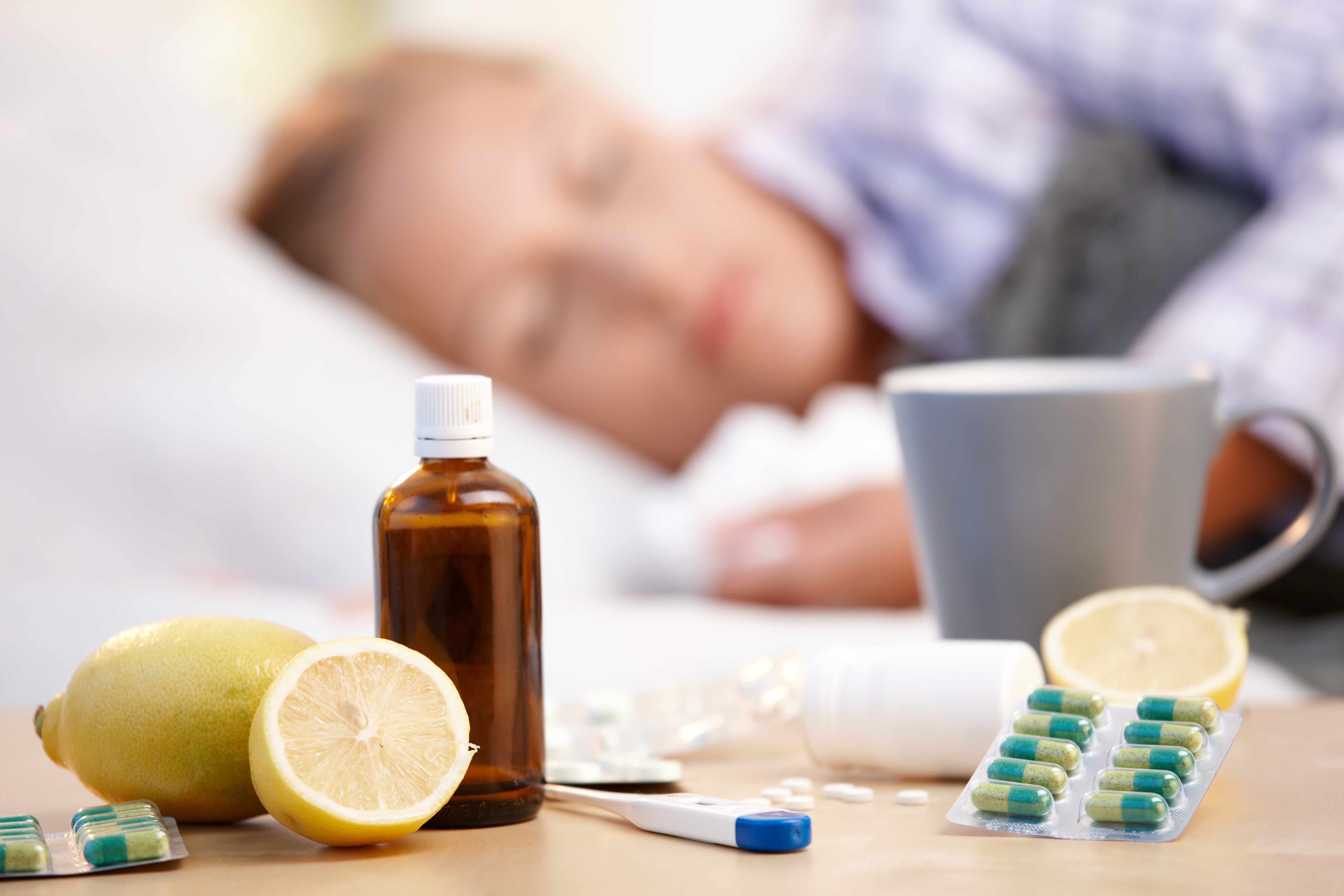 a sick person with a cold or flu, sleeping in bed with medications on the bedside table