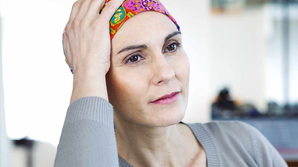 a close-up of a woman in a brightly colored headscarf, looking off into the distance