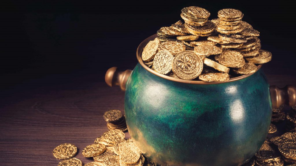 a green pot full of gold coins sitting on a table