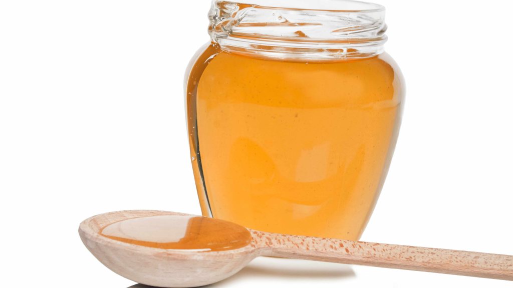 a jar of honey on a table with a wooden spoon