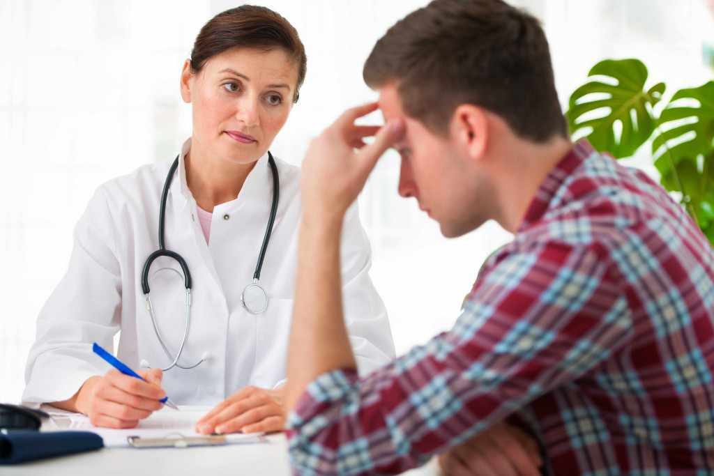 young man with female doctor in conversation about illness