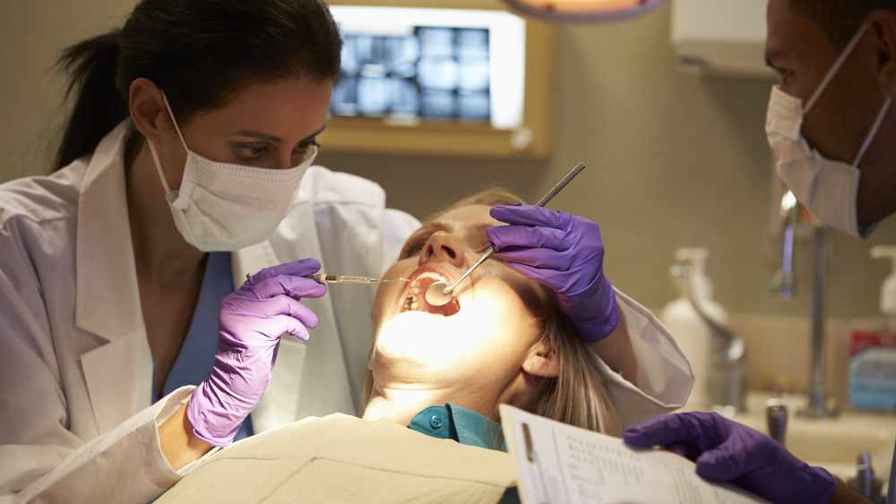 Dentists performing dental exam on female patient