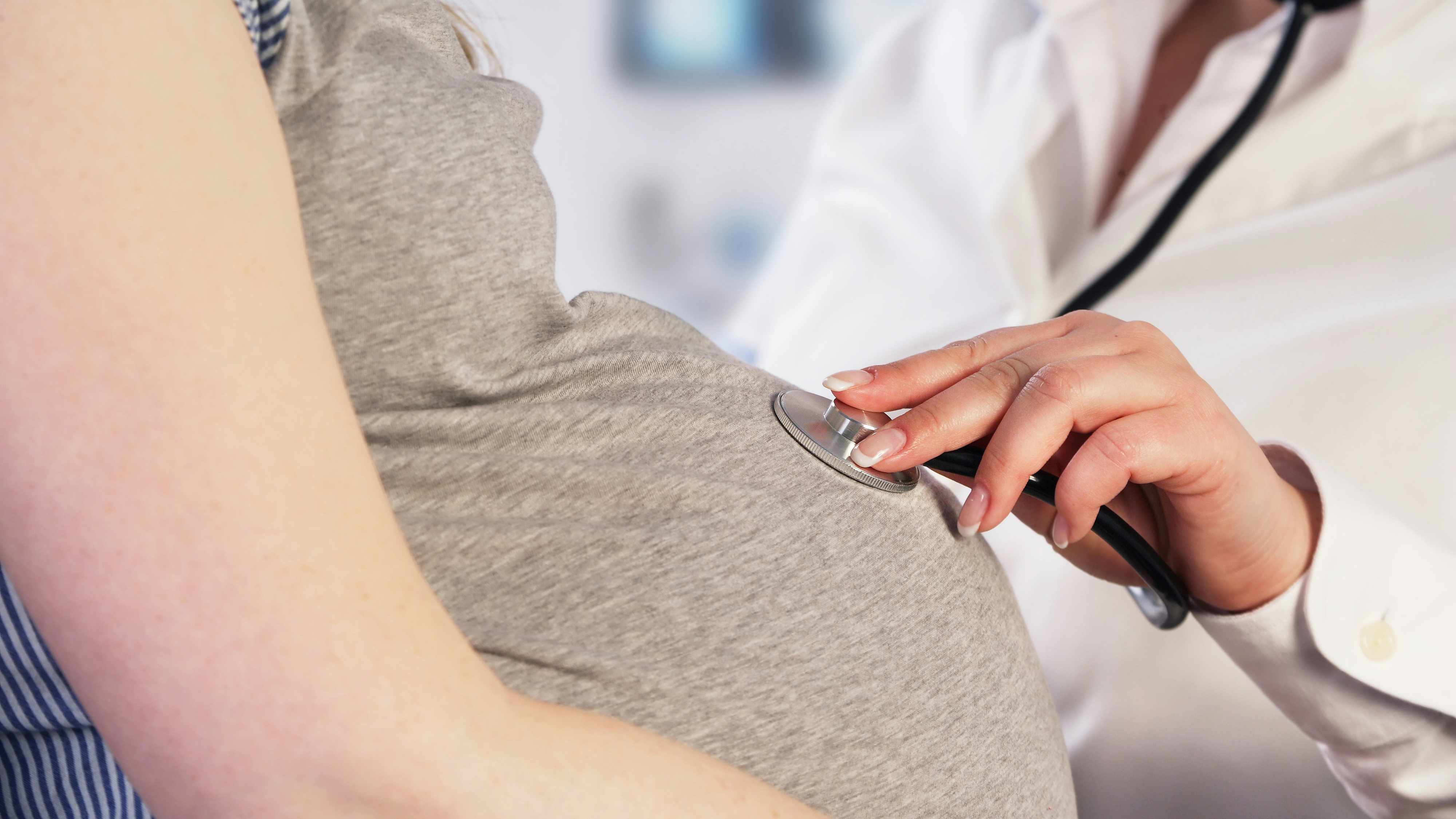 a pregnant women being examined at a doctor appointment with a stethoscope