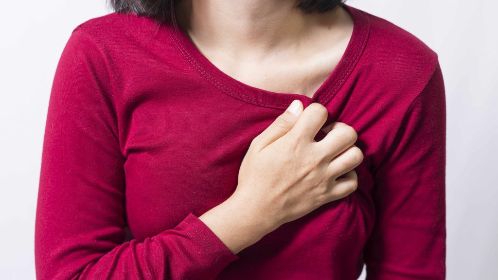 Una mujer se lleva la mano al pecho por el dolor de un posible ataque cardíaco. 