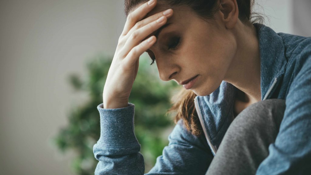 Una mujer se sostiene la cabeza mientras se muestra triste, deprimida y con pensamientos negativos 