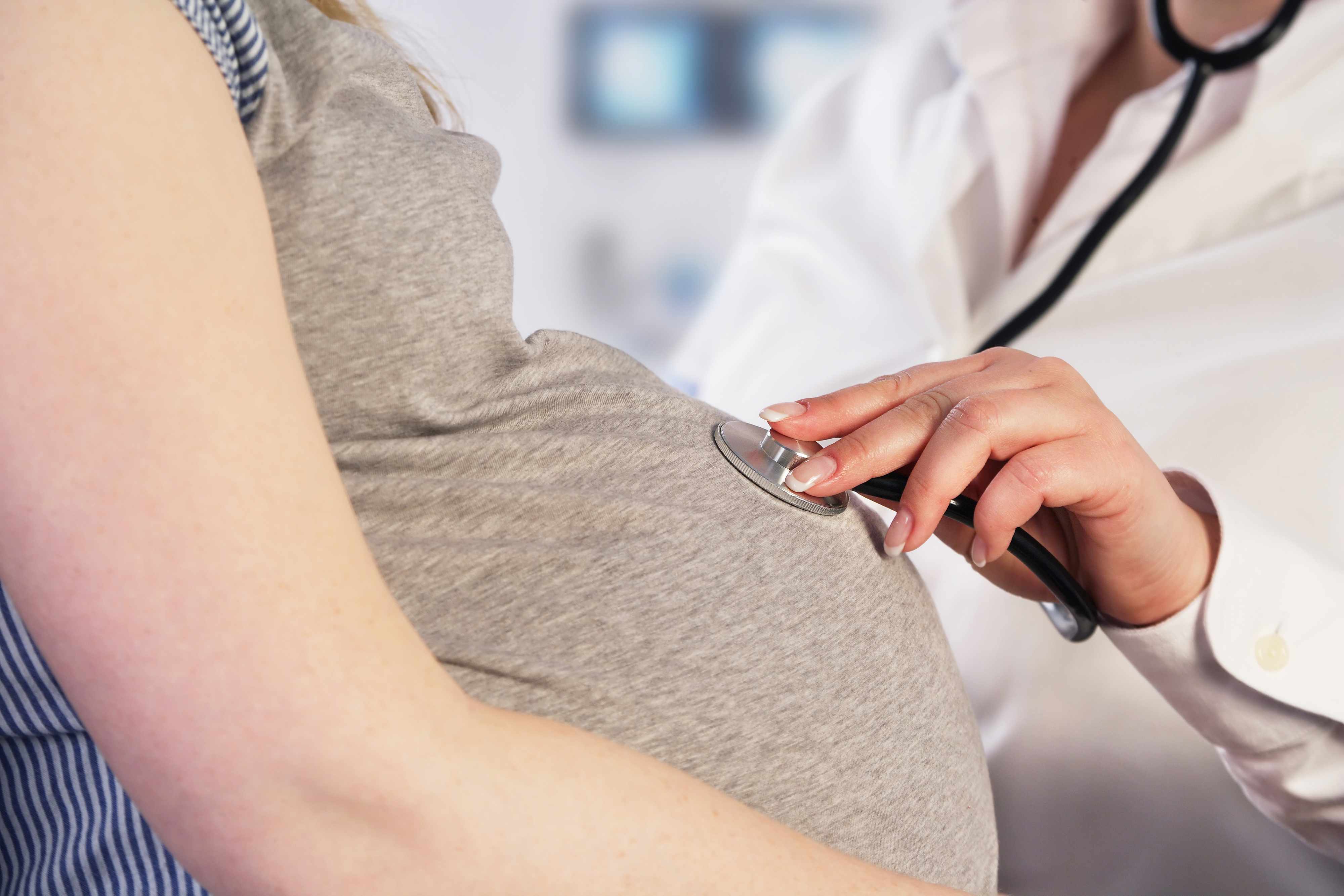 a pregnant women being examined at a doctor appointment with a stethoscope