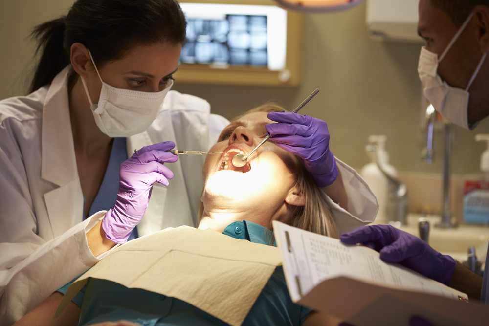 Dentists performing dental exam on female patient
