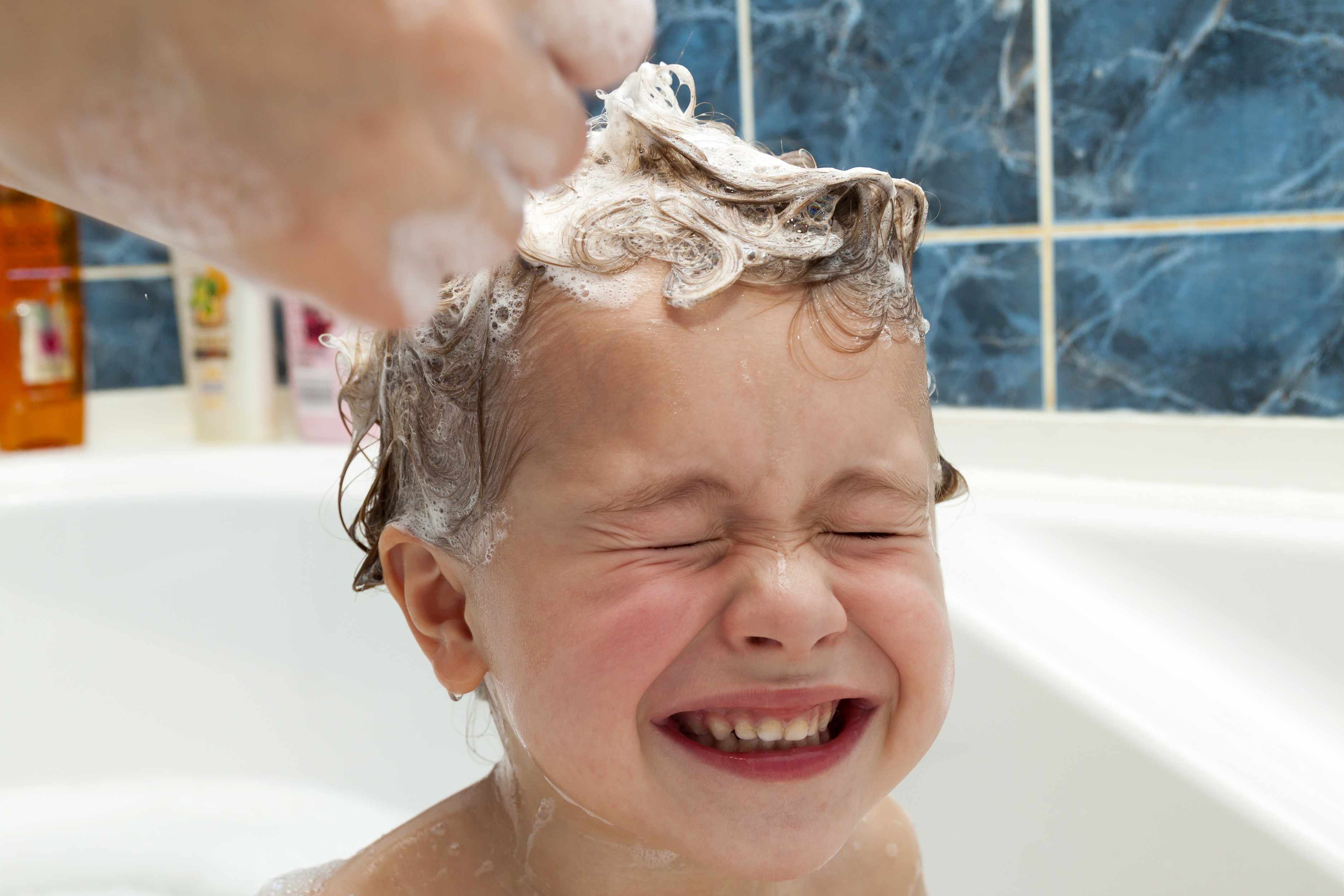a little boy or girl having hair washed with shampoo in a bathtub
