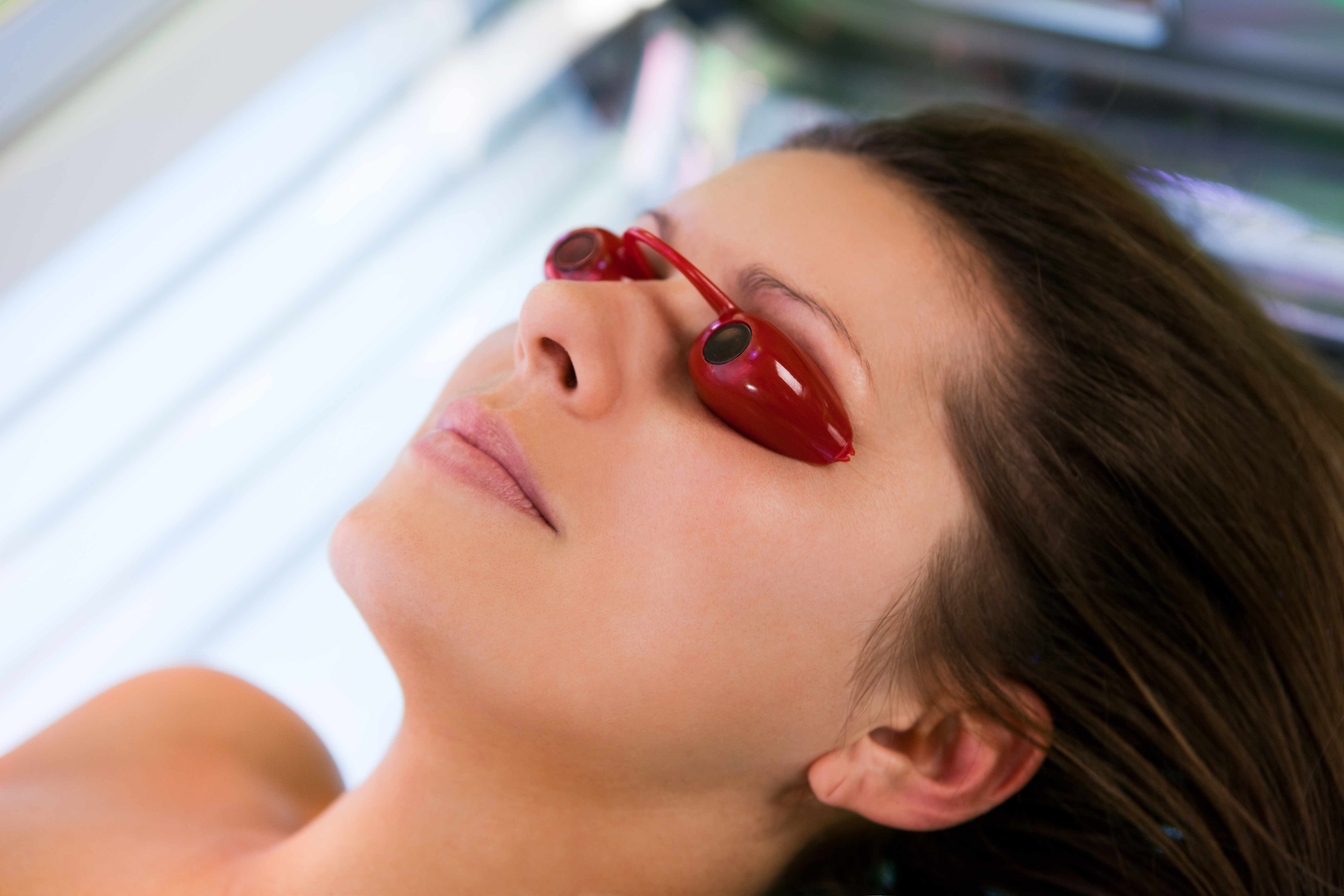 a young woman in tanning bed wearing eye protecting goggles