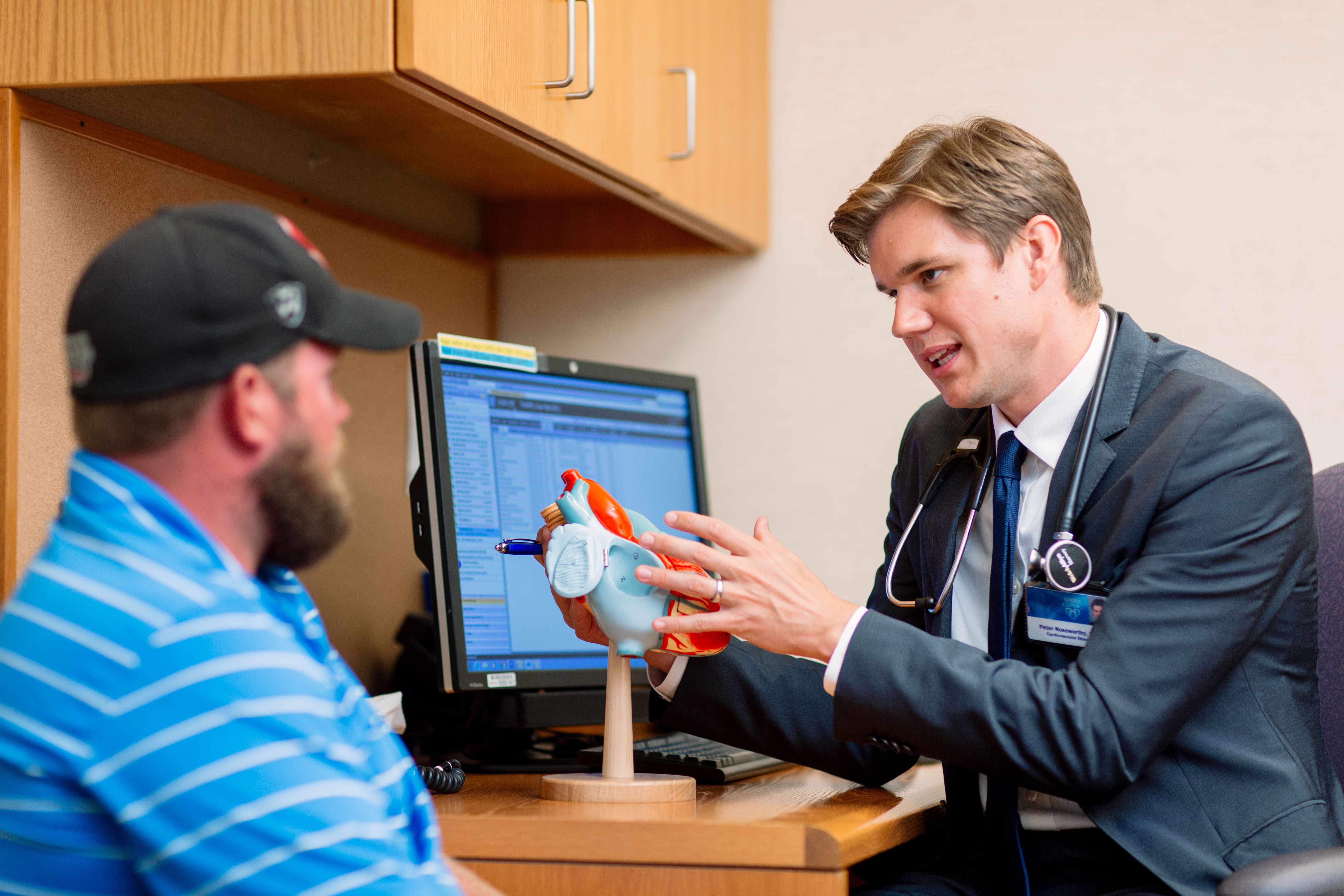physician explaining model heart to patient