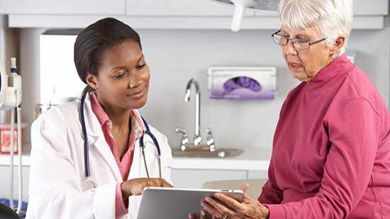 african-american female doctor nurse sharing information with an elderly woman in a hospital room during an appointment