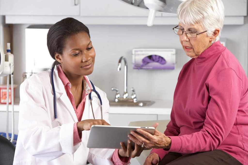 african-american female doctor nurse sharing information with an elderly woman in a hospital room during an appointment (original) diversity