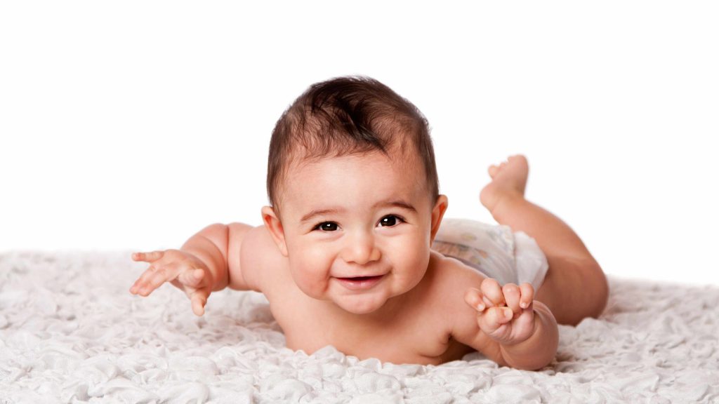 Un lindo y sonriente bebé acostado boca abajo