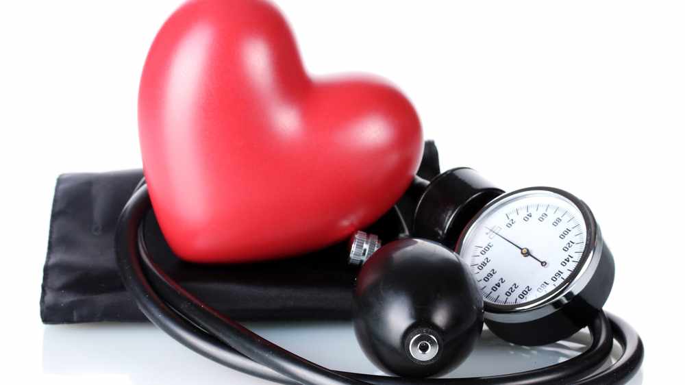 a blood pressure cuff and gauge, with a red plastic valentine heart