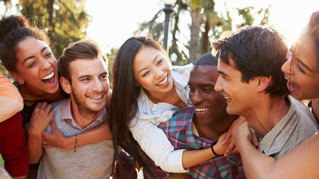 a diverse group of young people hugging and laughing, having fun