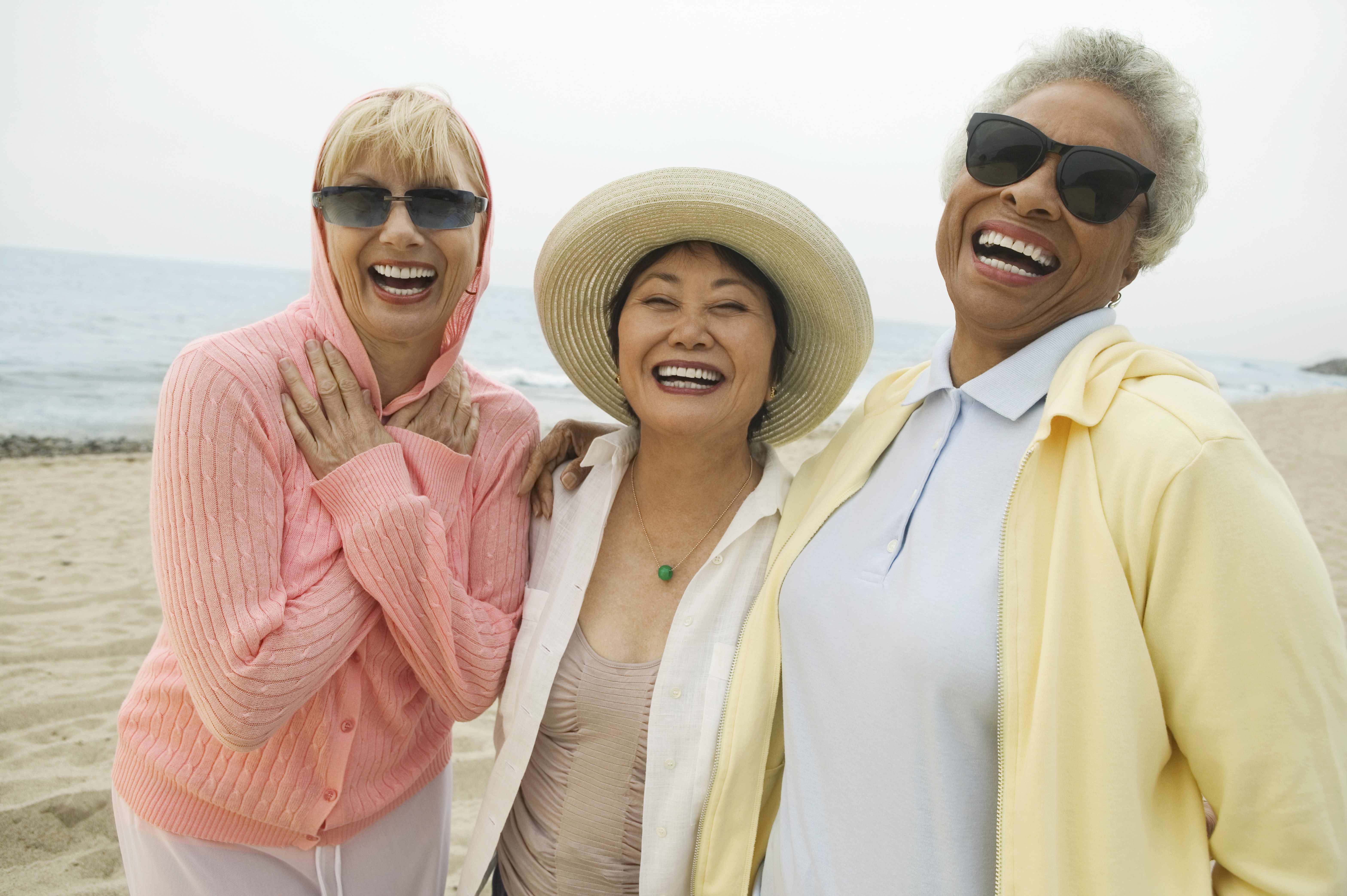 a group of diverse, middle-aged women friends walking on the beach and laughing