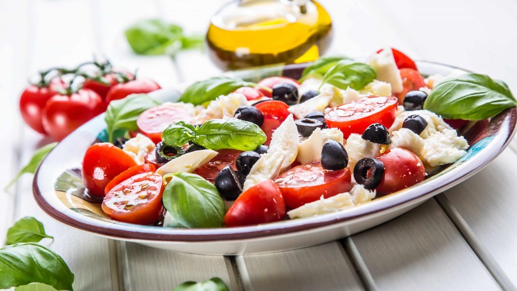Ensalada de la dieta mediterránea, con tomates, hojas de albahaca, aceitunas y pescado 