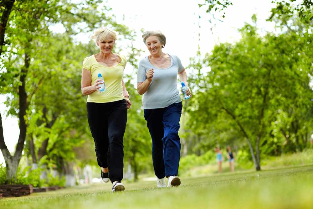 two middle-aged or senior women walking and exercising outside in a park