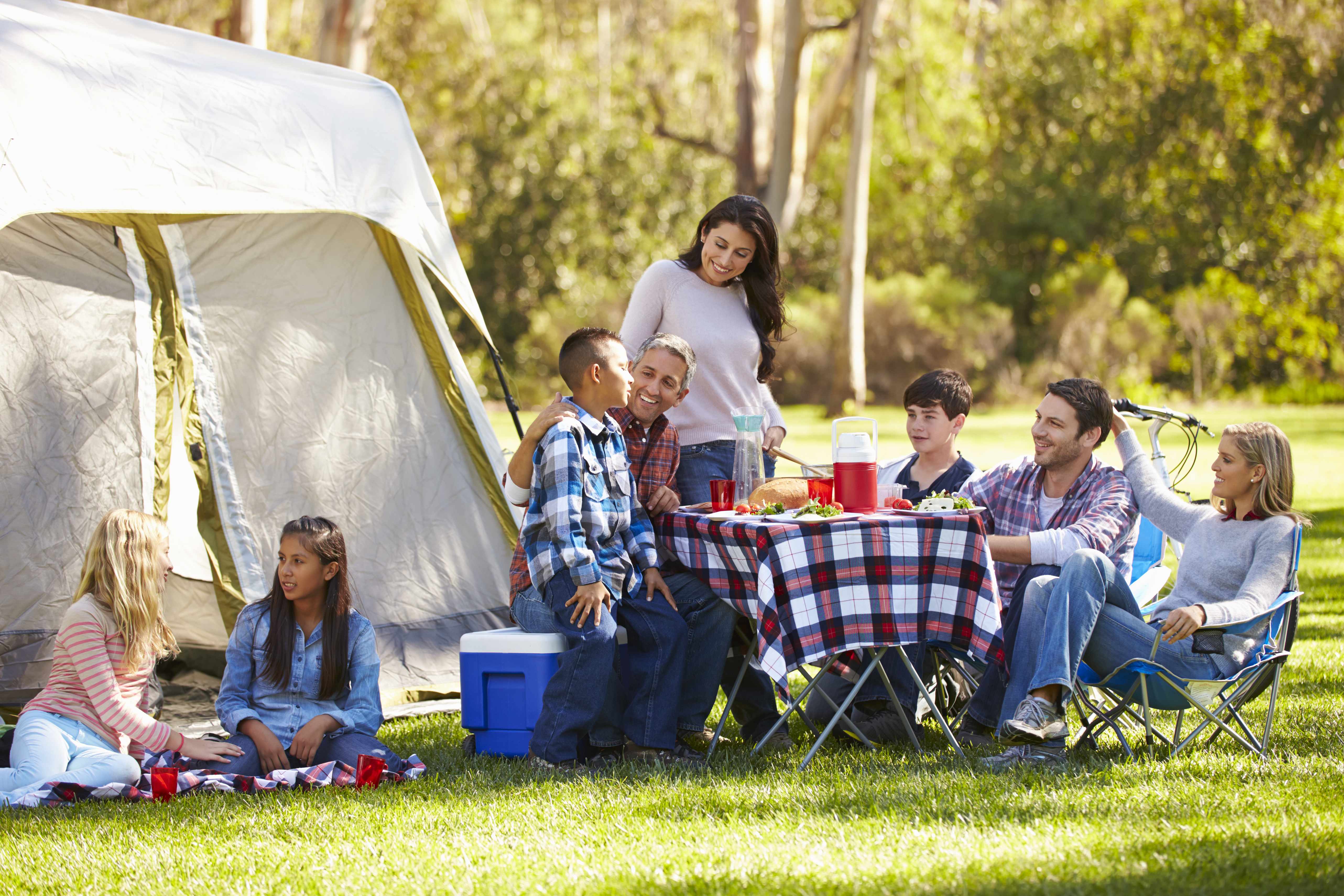 a family with friends outside camping and having an outdoor picnic