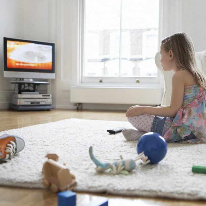 a little girl staring at a television screen, watching TV