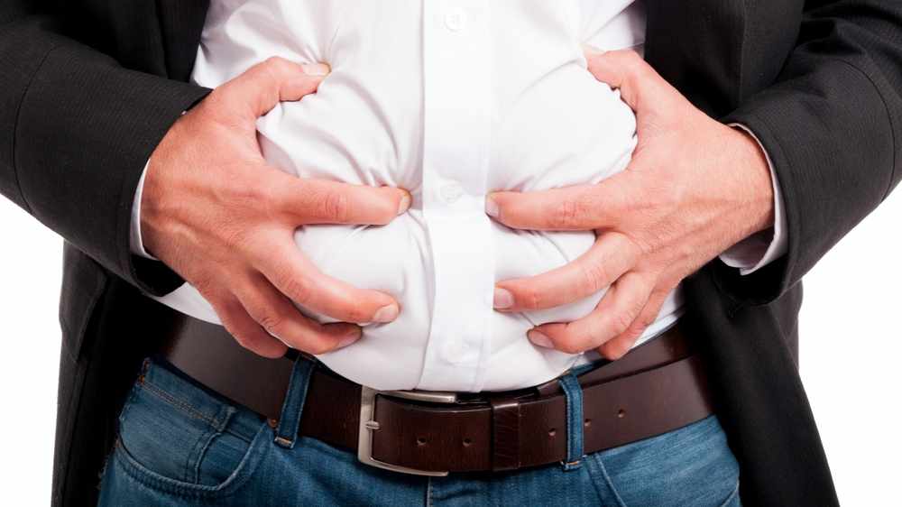 Un hombre aprieta su estómago porque tiene dolor o gases