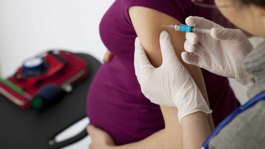 Una embarazada joven recibe una vacuna en la parte superior del brazo
